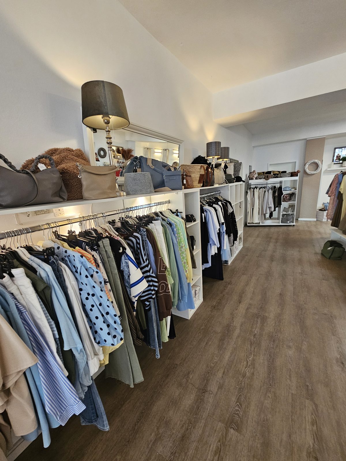 Kleiderständer mit Damenmode und Taschen im Regal